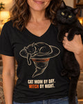 Close-up of the Cat Mom by Day. Witch by Night. V-neck tee: a black cat asleep in a witch hat, worn by a woman holding her black cat