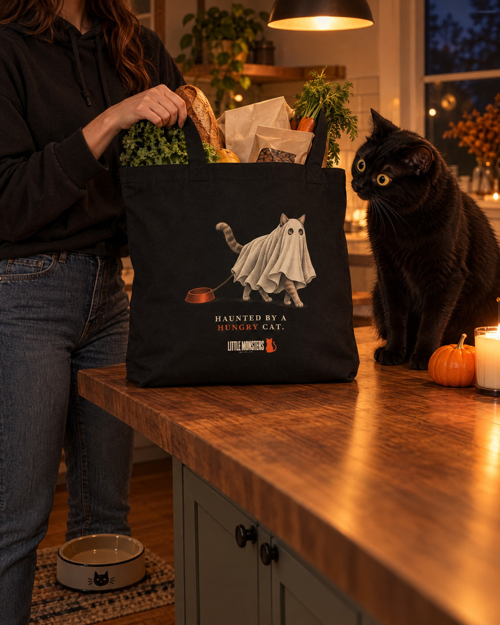Haunted by a Hungry Cat tote full of groceries on a kitchen counter, a black cat staring at it