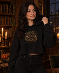 Woman in a candlelit library wearing the black Little Monsters Possessed Since Birth cropped hoodie with a black cat on a spirit board